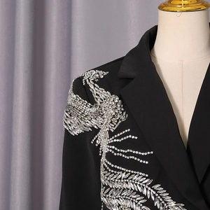 Gros plan détaillé sur la broderie plume en strass argentés sur l'épaule du blazer noir