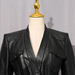 Detail of black leather jacket featuring V-neck and decorative stitching on front pockets