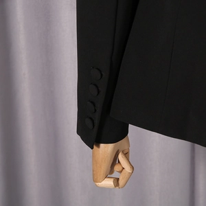 Detail of black blazer sleeve featuring four matching fabric-covered buttons on the cuff