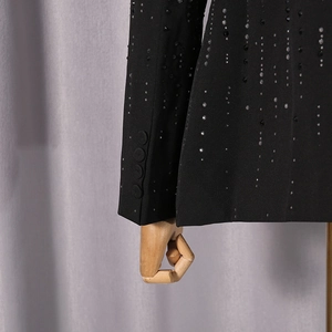 Close-up of black blazer sleeve with shimmering beadwork and matching fabric buttons