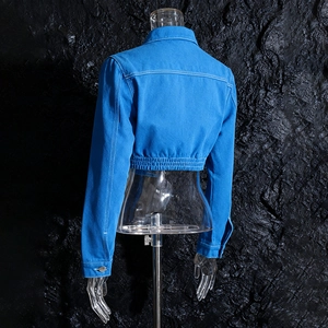 Dettaglio del retro della giacca in denim blu con cuciture bianche e orlo elastico aderente