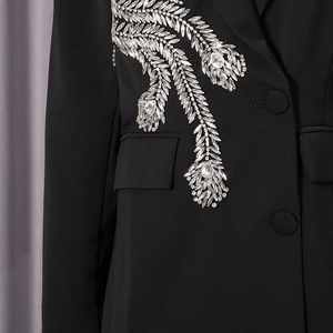 Détail d'un blazer noir avec broderie de plumes en cristal et boutons élégants