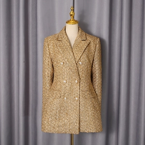 Detail of tweed blazer showing woven texture, golden metallic fibers, and pearl buttons