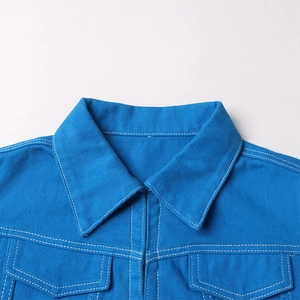 Dettaglio della giacca di denim azzurro con cuciture bianche a contrasto e tasche a pattina