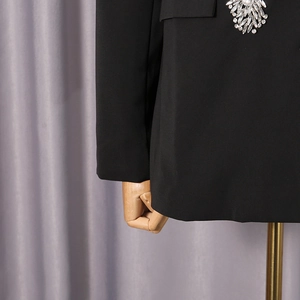 Vue détaillée d'une broche en strass argentés sur une veste de blazer noire ajustée