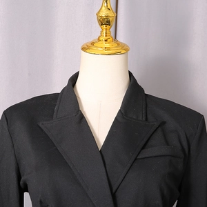 Close-up of slim fit black bodysuit featuring sharp peak lapels and a refined chest pocket