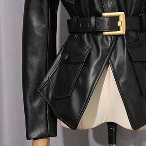 Detail of black faux leather jacket featuring a wide belt with a large gold square buckle
