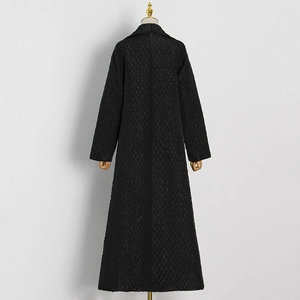 Detail view of black quilted long coat featuring premium textured fabric and lapel collar