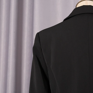 Gros plan de l'épaule arrière et du col d'un blazer noir montrant la texture du tissu