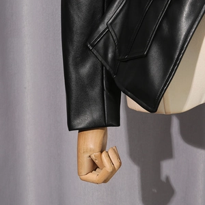 Close-up of black leather jacket featuring flap pocket and premium stitching detail