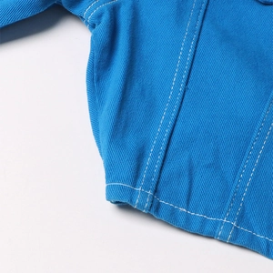 Dettaglio ravvicinato del tessuto denim blu con cuciture a contrasto bianche e trama
