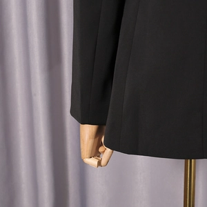 Gros plan détaillé de la texture du tissu noir du blazer sur un mannequin de bois