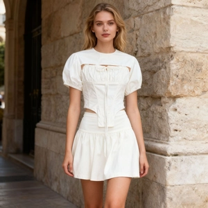 Detail of white two-piece set featuring puff sleeves, lace-up cutout and pleated skirt