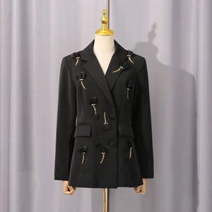 Detailansicht der schwarzen 3D-Blumenapplikation und Goldkettenfransen am Damen-Blazer