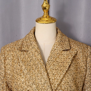 Detailed macro view of gold tweed fabric with metallic yarn and classic lapel design