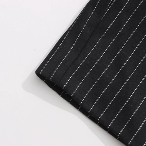 Close-up of black pinstripe wool blazer fabric showing fine texture and hem stitching