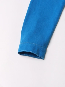 Dettaglio del polsino della giacca di jeans blu con cuciture bianche a contrasto