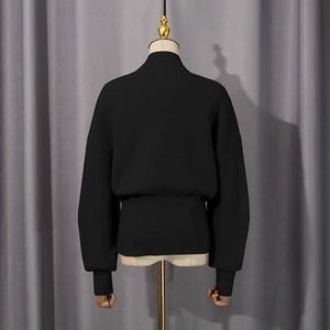 Detail view of black ribbed knit sweater featuring a thick texture and elastic hem design