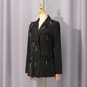 Detail der 3D-Blumenapplikation und goldener Perlenfransen an einem schwarzen Blazer