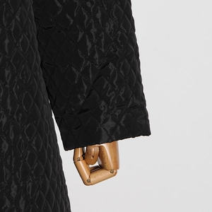 Detail of the black quilted texture with diamond pattern on the long sleeve jacket