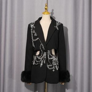 Détail d'un blazer noir ajouré à la taille avec broderies strass et poignets en fourrure