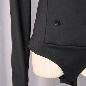 Detail shot of black long-sleeve bodysuit featuring button accents and snap closure