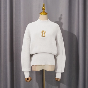 Detail of white knit sweater with golden keyhole cutout and vertical ribbed texture