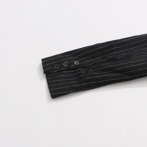 Detailed close-up of striped suit cuff featuring three dark round buttons on black fabric