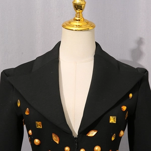 Detail von bernsteinfarbenem Edelsteinschmuck auf einem schwarzen Langarmkleid