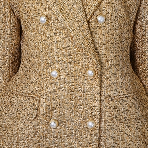 Detail of gold tweed fabric with metallic threads and ornate white pearl buttons