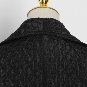 Detail view of the black diamond-quilted pattern and glossy collar on this winter coat