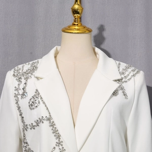 Gros plan d'un blazer blanc avec motifs floraux complexes en strass et paillettes argentés