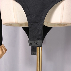Detail view of black knit bodysuit featuring double metal snap button crotch closure