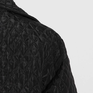 Detailed macro view of diamond quilted pattern and silk texture on black cotton coat