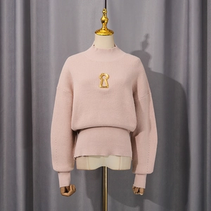 Detail of pink knit sweater featuring vertical stripes and a gold keyhole metal ornament