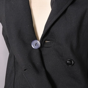 Detailed close-up of peak lapels and contrast buttons on a slim black bodysuit