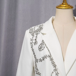 Détail d'un blazer blanc avec broderie complexe de fleurs en strass argentés