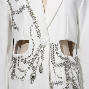 Détail du blazer blanc avec motifs floraux en strass et découpes à la taille