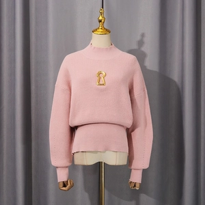 Detail view of pink turtleneck sweater featuring a golden keyhole metal decoration