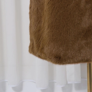 Detailed macro view of the premium caramel brown faux fur texture and long pile hem