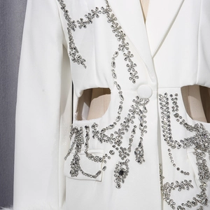 Gros plan du blazer blanc ajouré orné de strass floraux et de chaînes élégantes