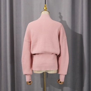 Detail view of pink knit sweater back with ribbed hem and vertical texture patterns