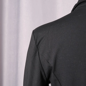 Detail of a black tailored bodysuit showing the weave texture and shoulder seam stitching