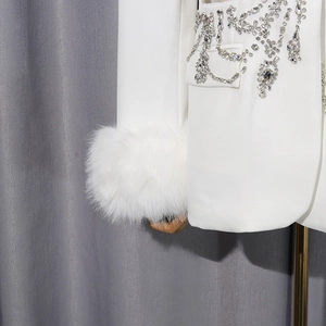 Détail d'un blazer blanc avec poignets en fausse fourrure et broderie de strass