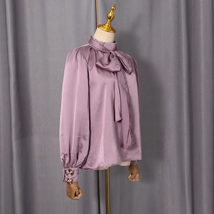 Détail du chemisier en satin avec nœud papillon chic et texture élégante violette