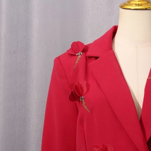 Detail eines roten Blazers mit 3D-Blumenapplikation, Goldperlenquasten und Strassakzenten