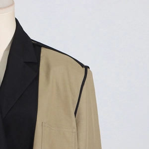 Detail of khaki and black contrast patchwork blazer showing neckline and shoulder seams