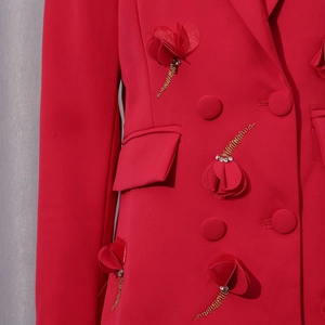Detail eines roten Blazers mit 3D-Blütenapplikationen und funkelnden Goldperlenfransen