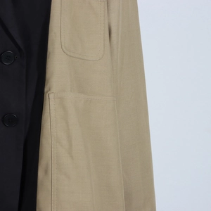 Detail of color-block blazer featuring contrast stitching and black button closure