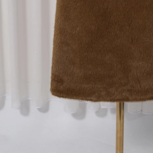Close-up of brown faux fur wool coat hem with soft texture and golden metal rack